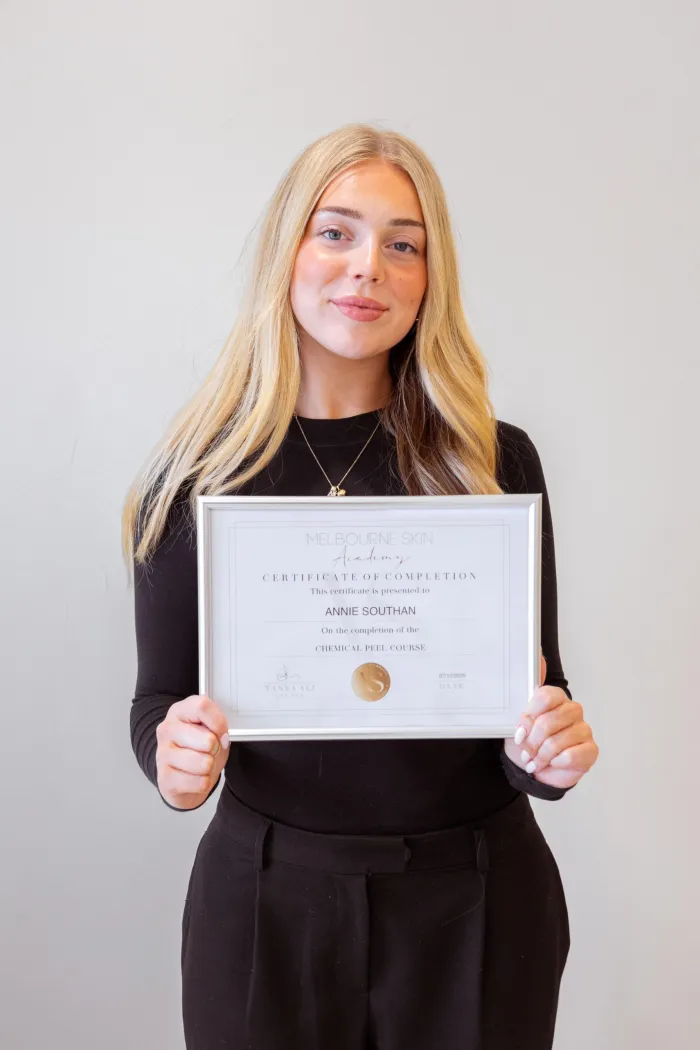 Skin academy graduate holding her certificate